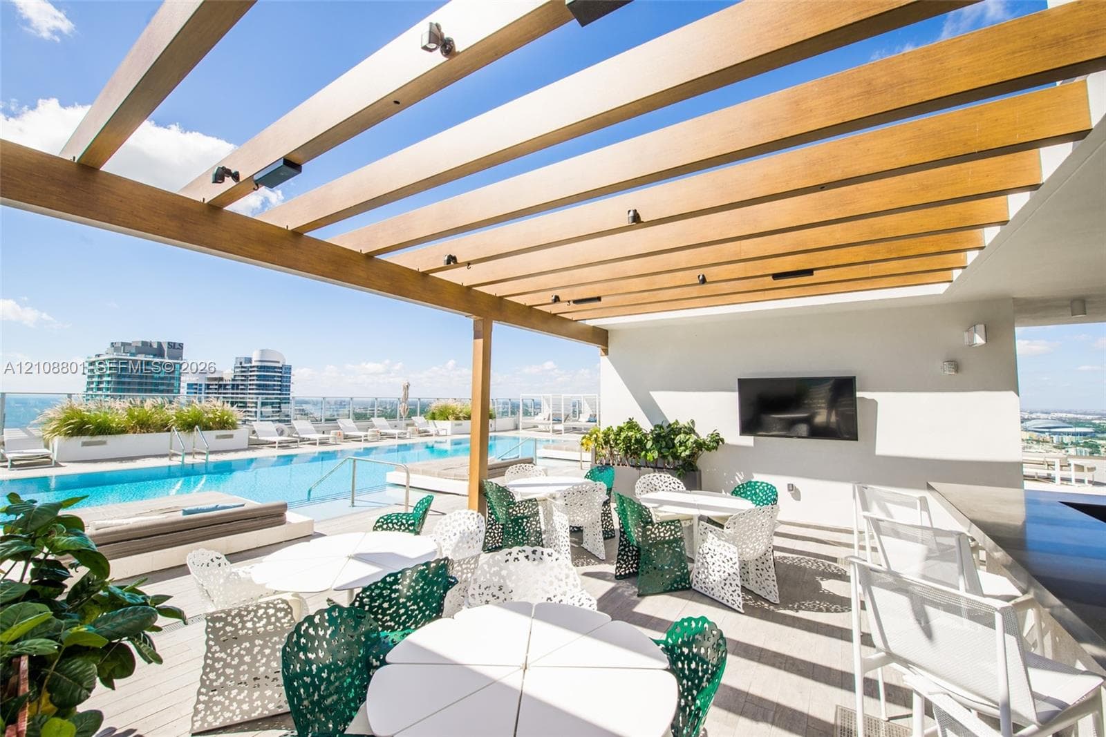 Rooftop terrace featuring an infinity-edge swimming pool, wood-finish pergola with integrated lighting, wall-mounted television, and built-in planters