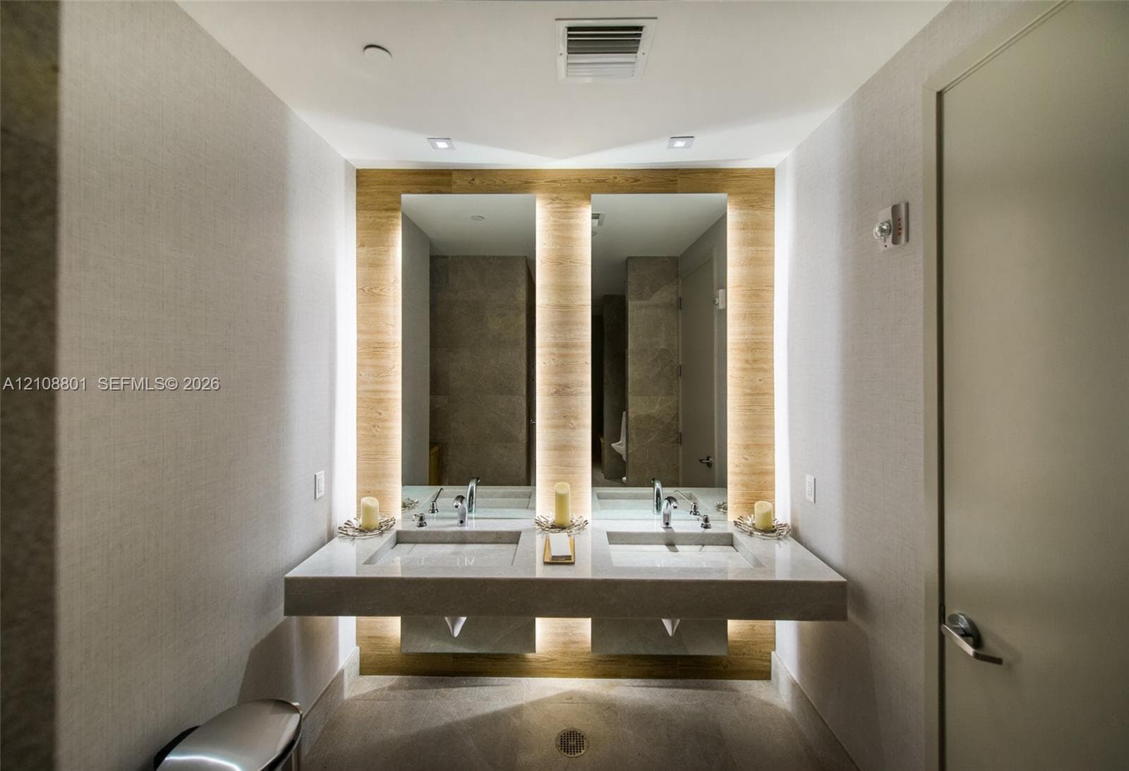 Floating dual vanity with stone countertops, integrated backlighting, dual inset mirrors, and wall-mounted faucets