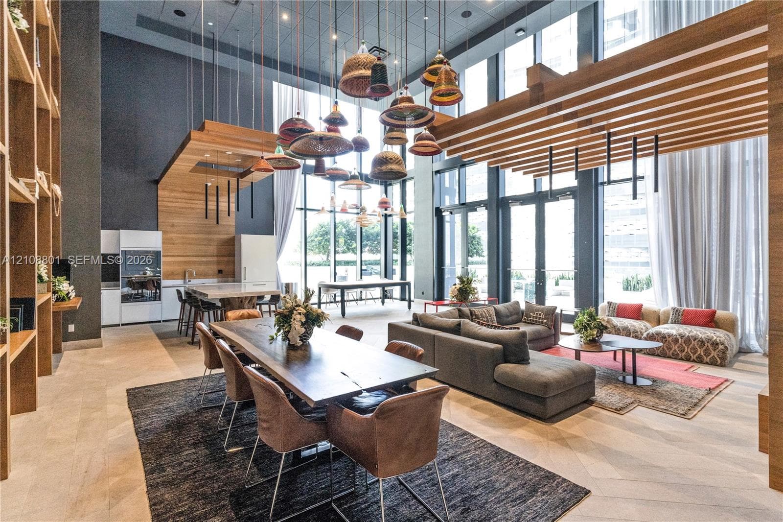 Double-height floor-to-ceiling glass walls, wood-slat ceiling accents, custom built-in shelving, herringbone wood-finish flooring, and statement pendant lighting