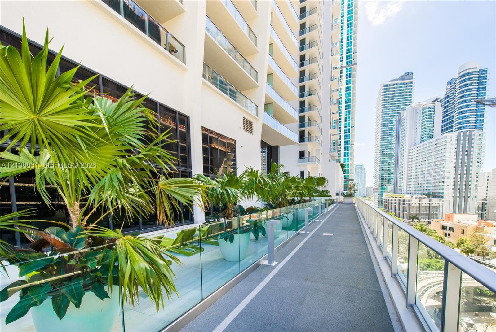 Expansive outdoor terrace featuring glass panel railings, concrete flooring, and built-in landscape planters
