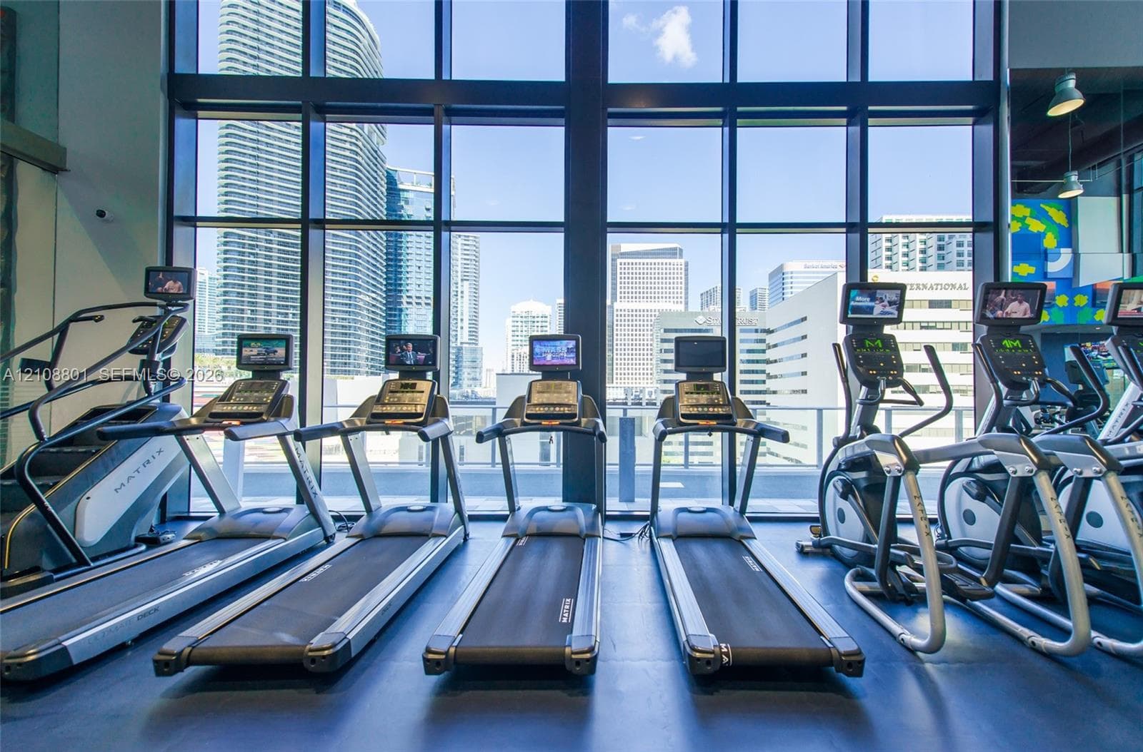 Fitness center featuring floor-to-ceiling windows, natural light, and professional-grade cardiovascular equipment
