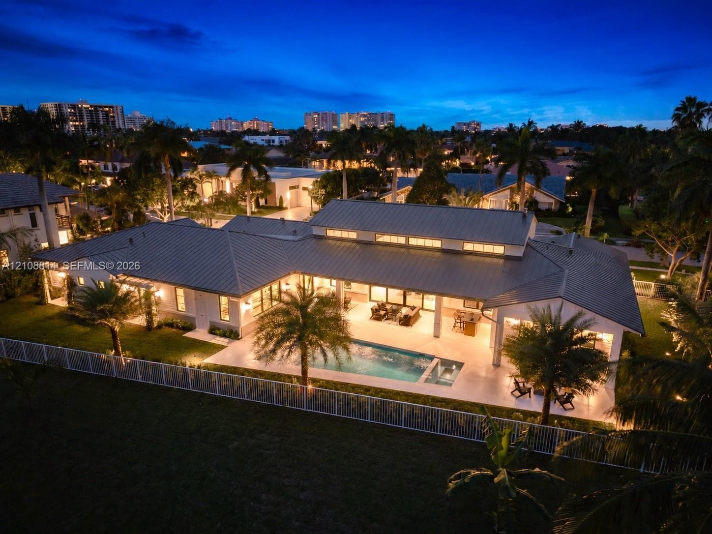 Single-story residence featuring a metal roof, clerestory windows, an expansive covered patio, a rectangular swimming pool, and a fenced perimeter