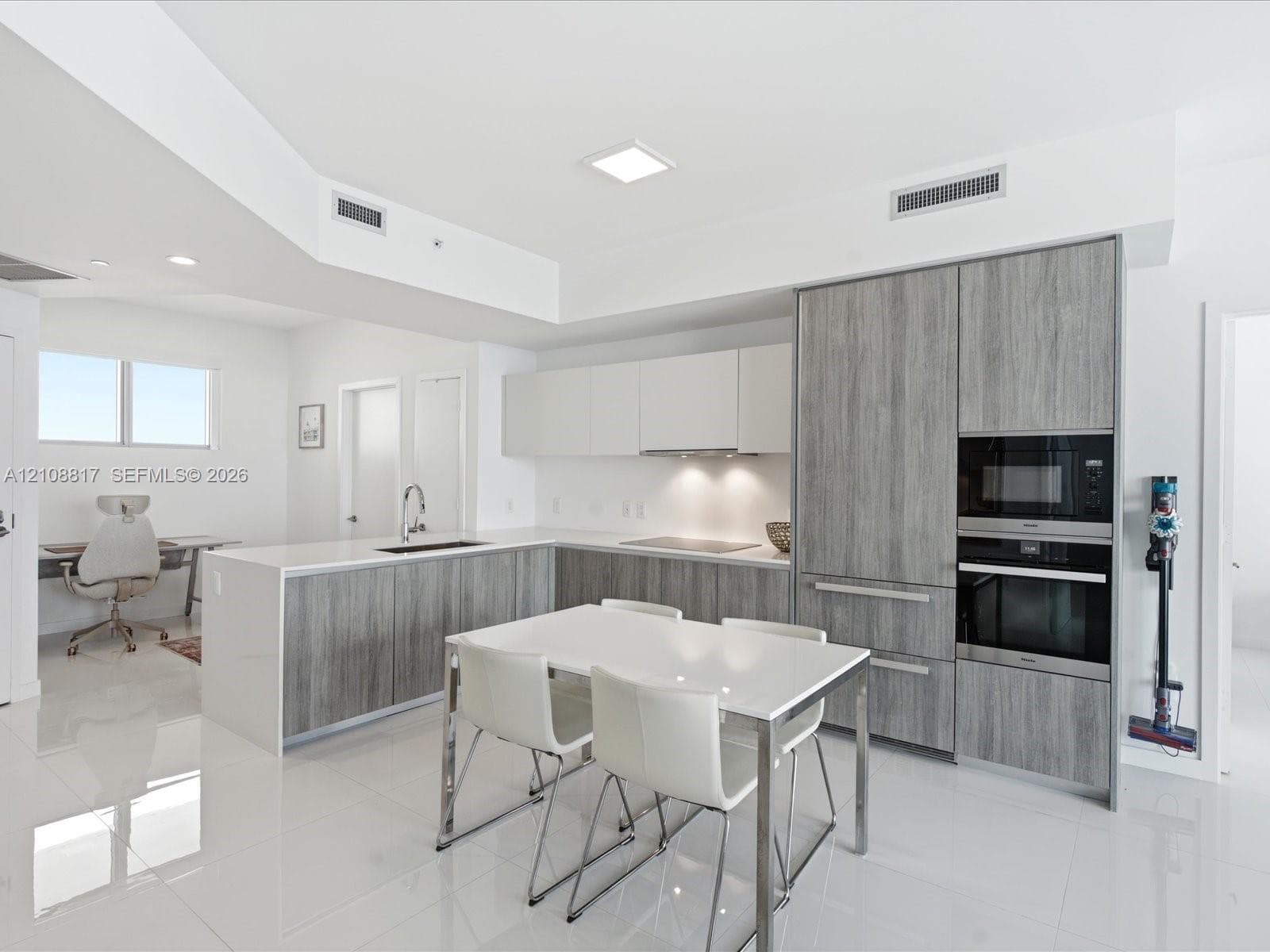 Modern kitchen featuring wood-finish cabinetry, quartz countertops, integrated wall ovens, and high-gloss tile flooring