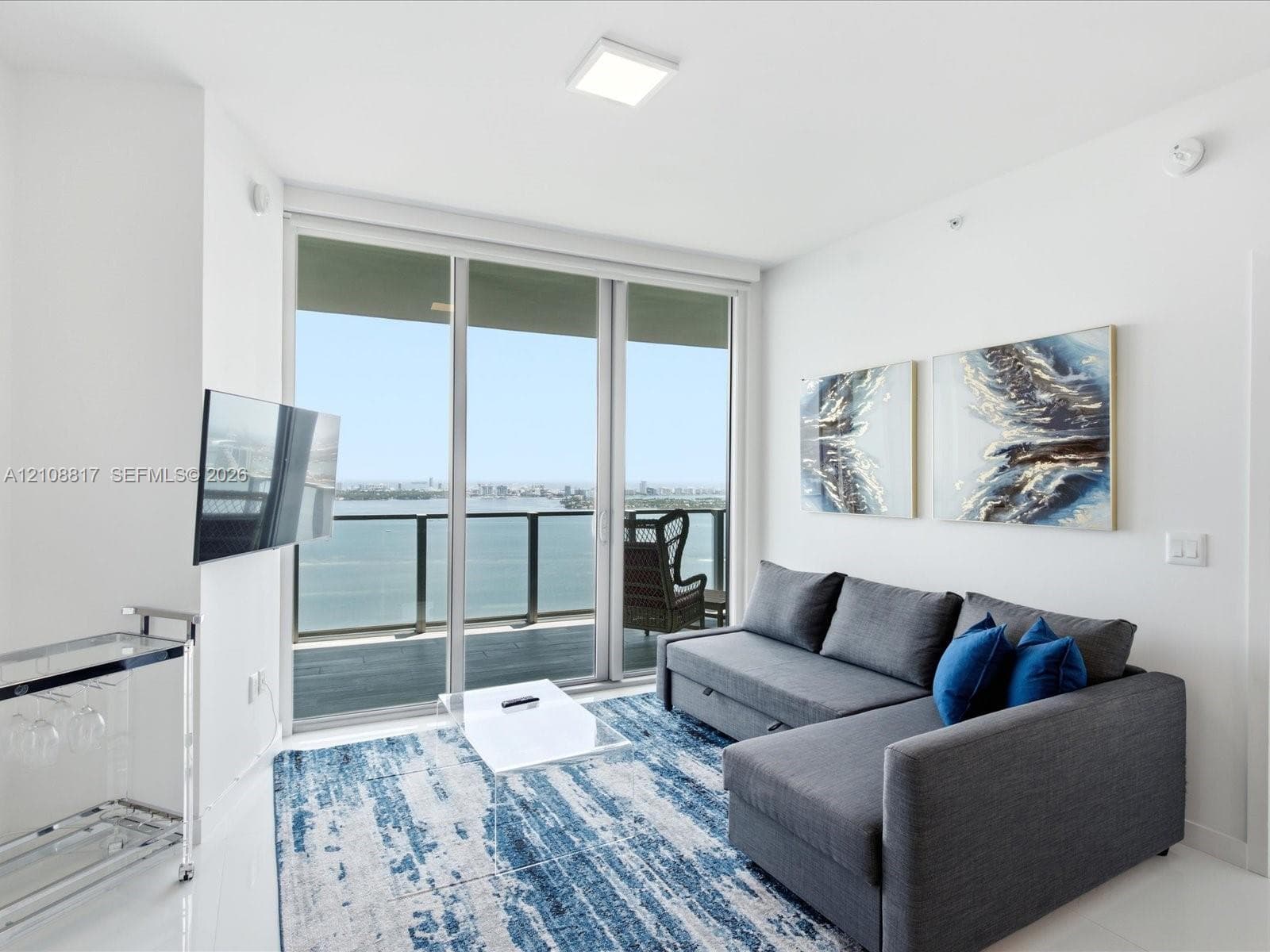 Floor-to-ceiling sliding glass door, private balcony with metal railing, and neutral flooring