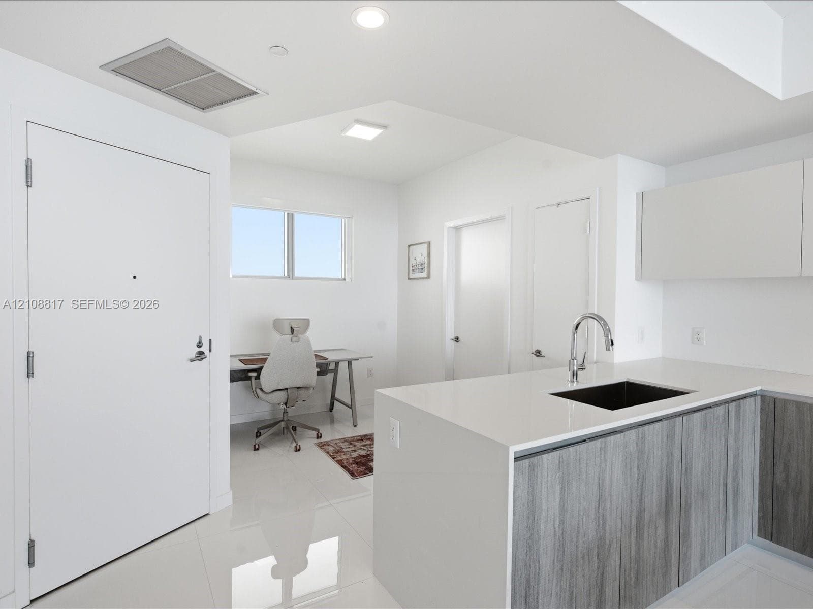 Kitchen featuring stone-finish countertops, grey wood-finish cabinetry, a square undermount sink with a gooseneck faucet, and polished tile flooring