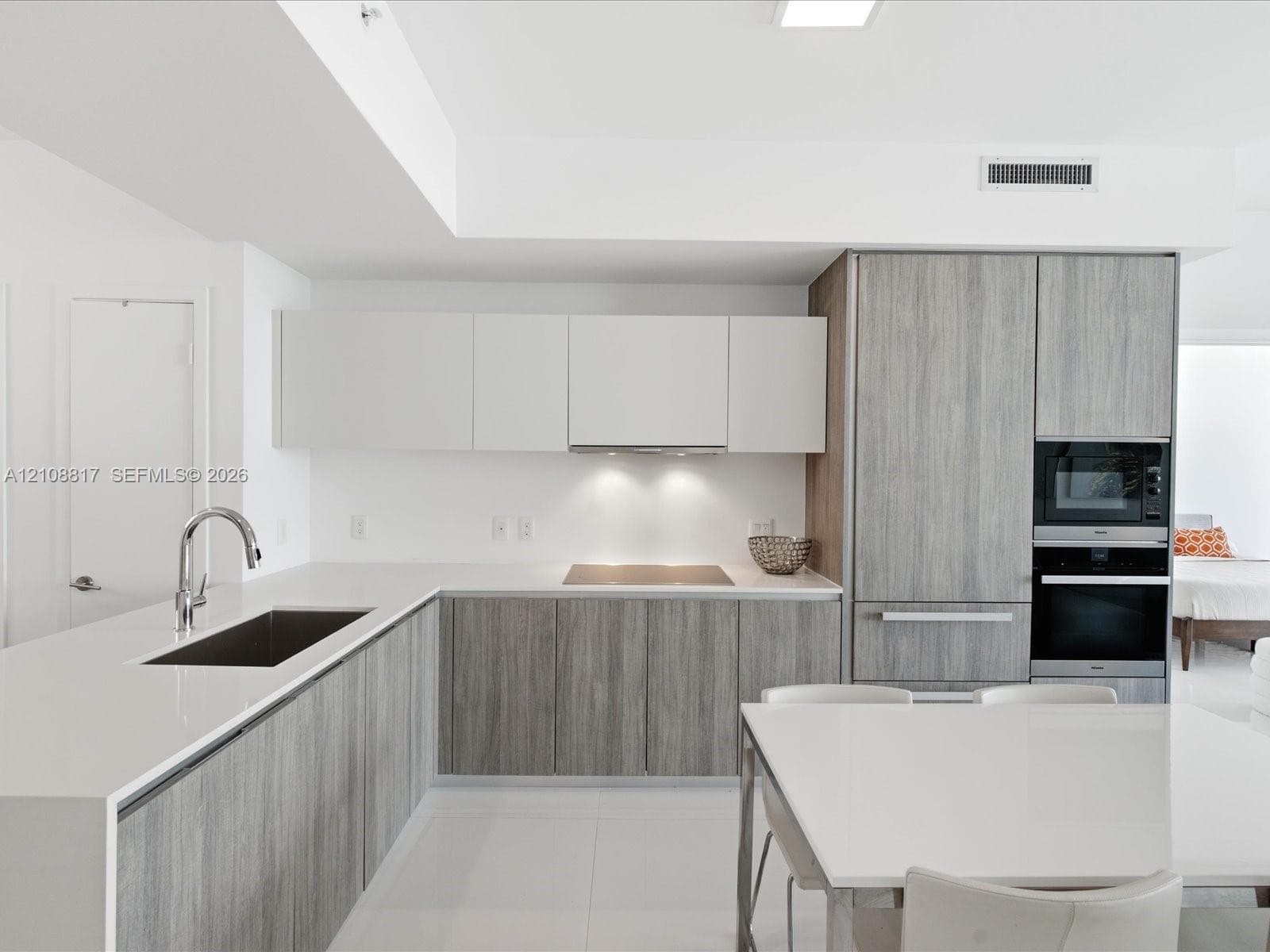 Contemporary kitchen featuring dual-tone cabinetry, quartz countertops, integrated stainless steel appliances, and a recessed stainless steel sink with a high-arch faucet