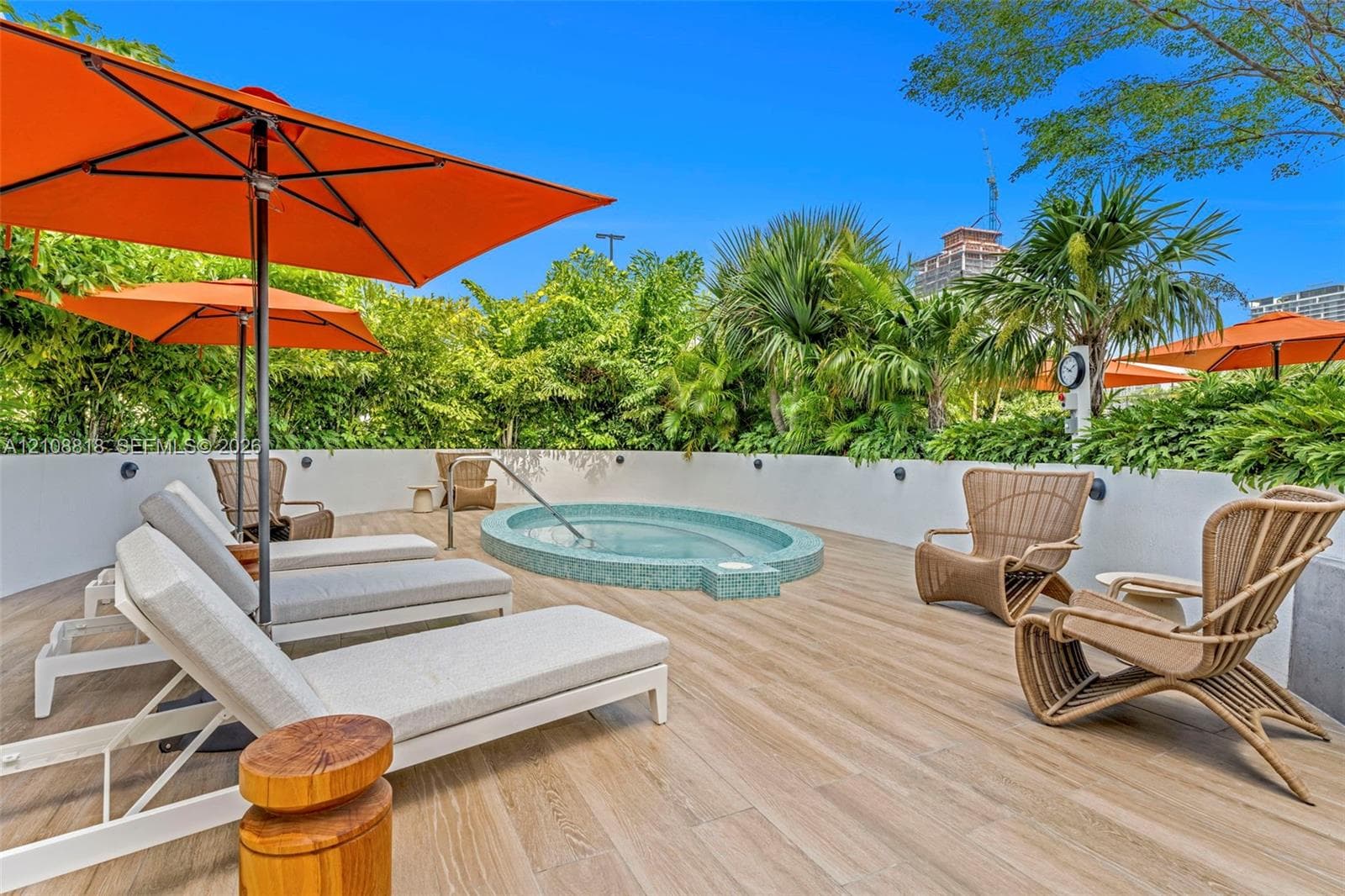 Outdoor terrace featuring wood-finish tiling, a built-in circular spa with tiled surround, and perimeter privacy wall
