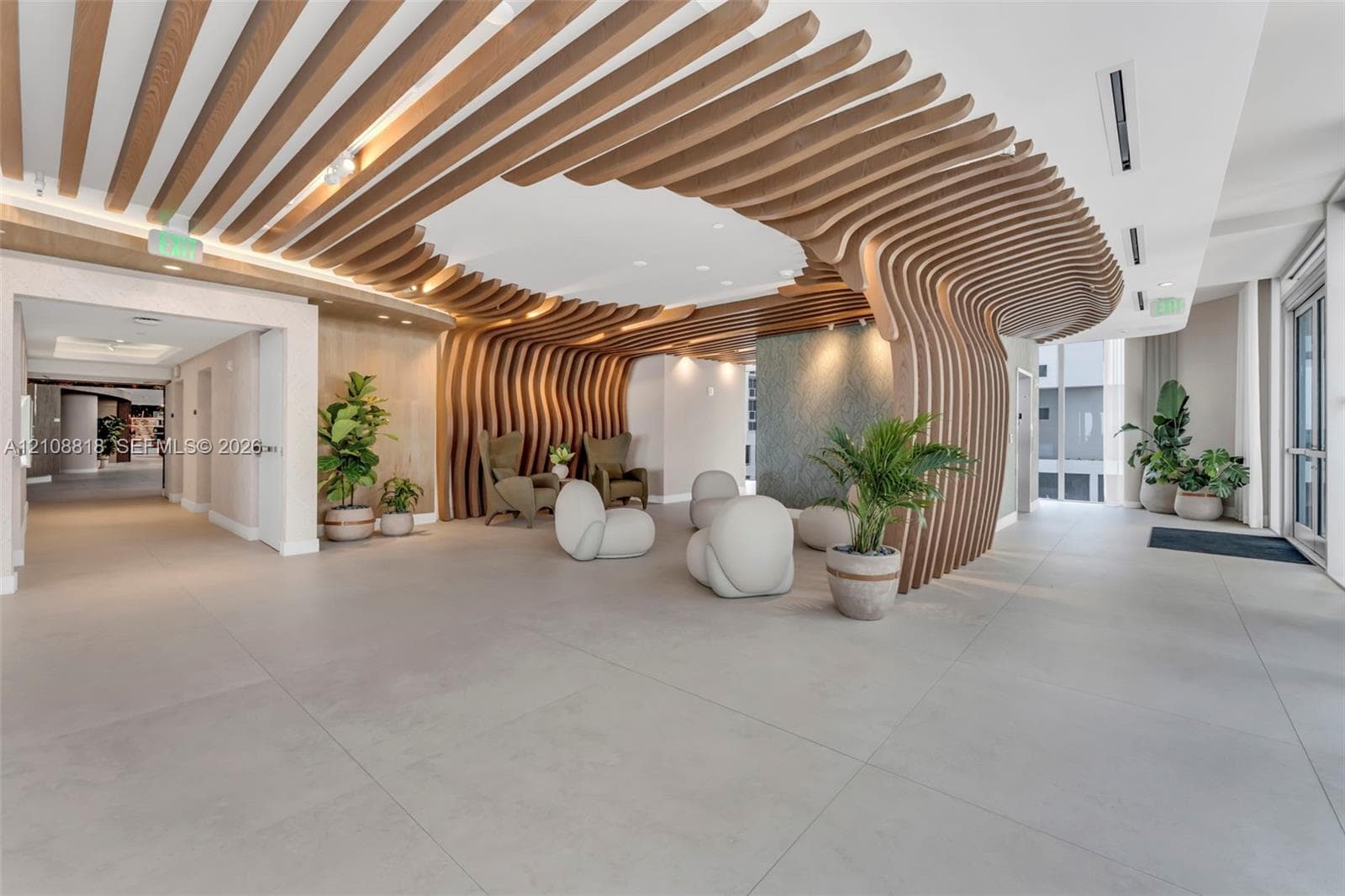 Expansive lobby featuring large-format tile flooring, a custom wood-slat ceiling installation with curved architectural detailing, and recessed lighting