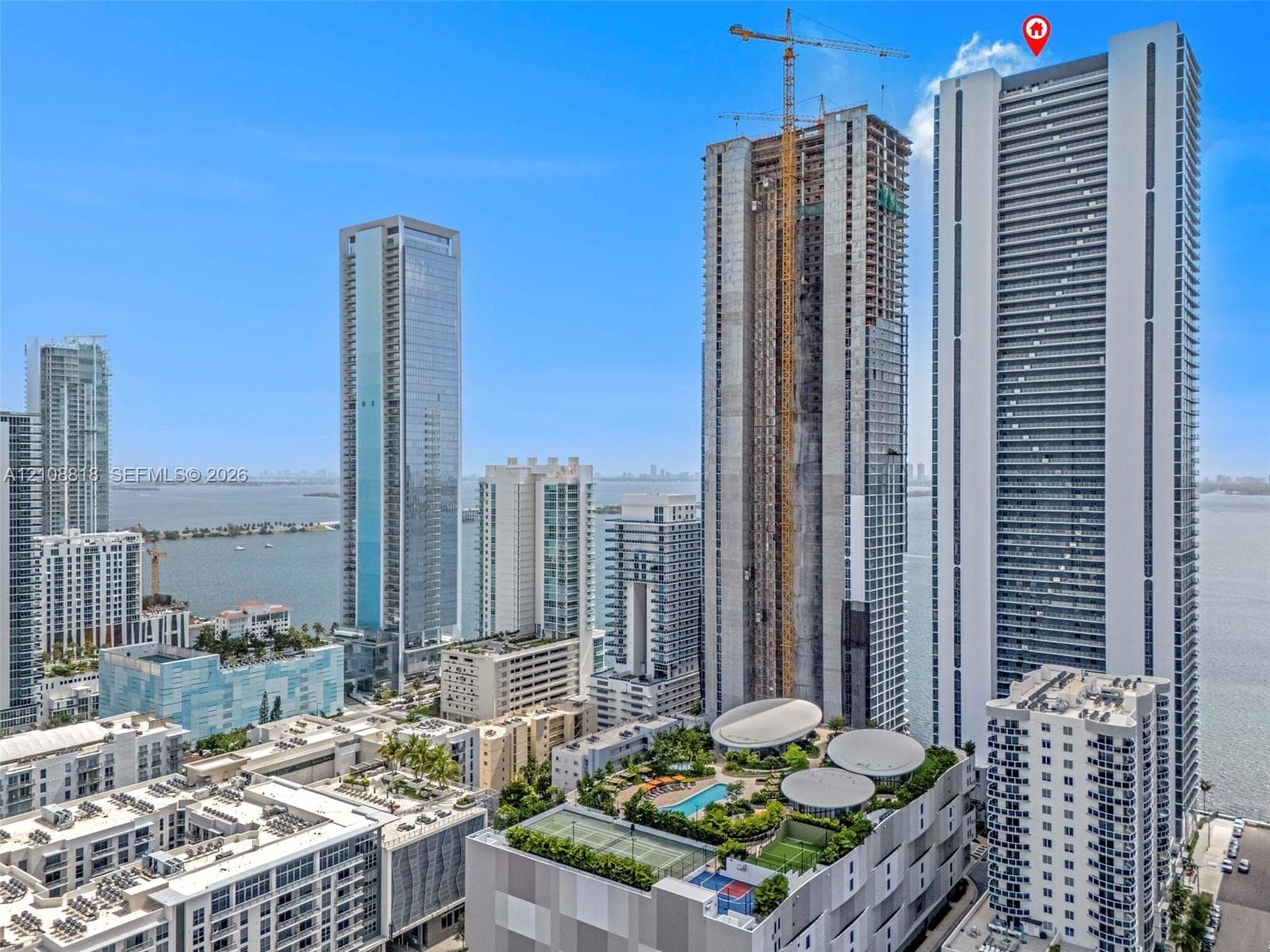 High-rise residential tower featuring a glass facade, expansive balcony tiers, proximity to the waterfront, and a multi-level structure with integrated architectural elements
