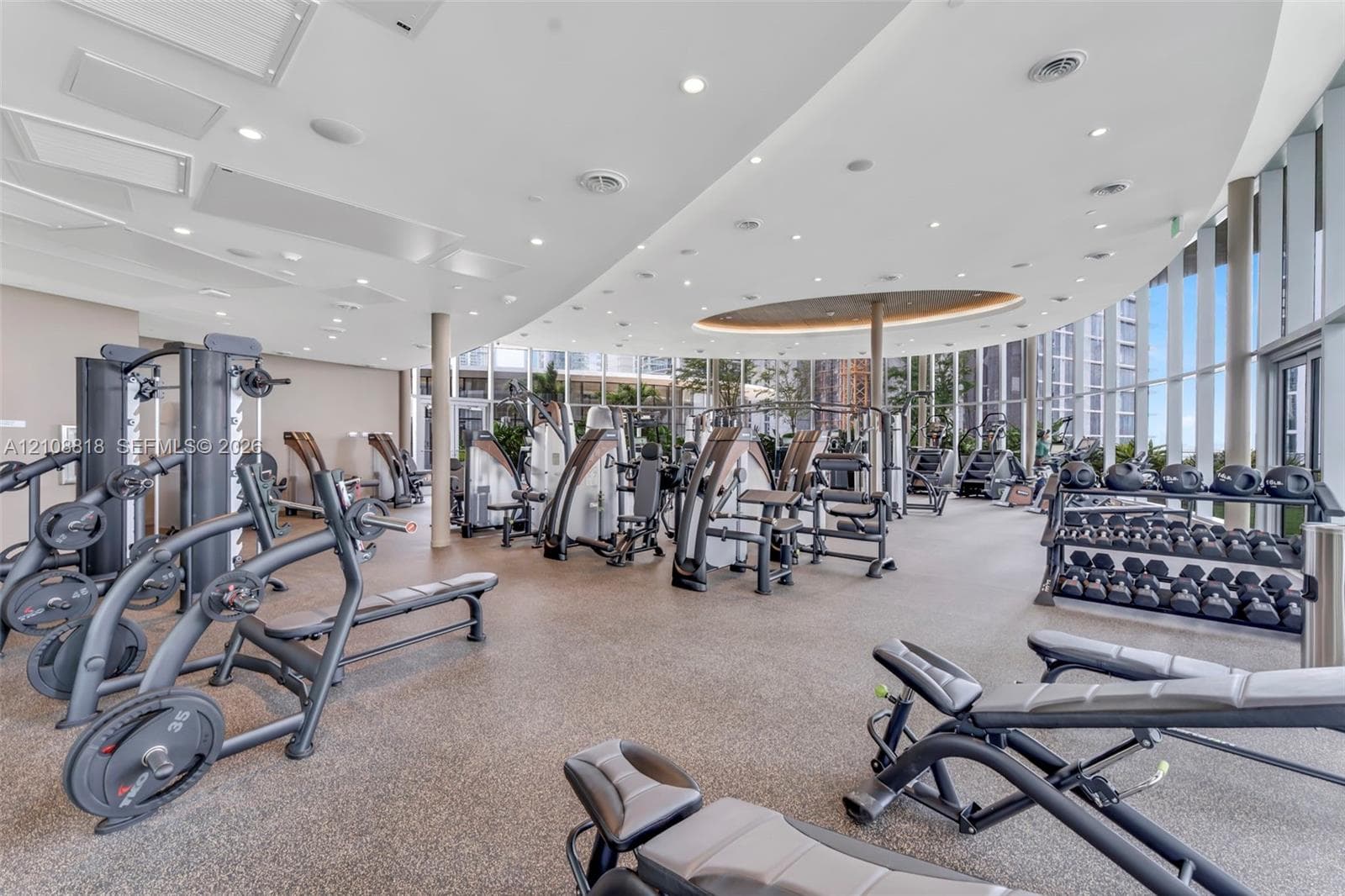 Fitness center featuring a curved ceiling with recessed lighting, floor-to-ceiling windows, and resilient athletic flooring
