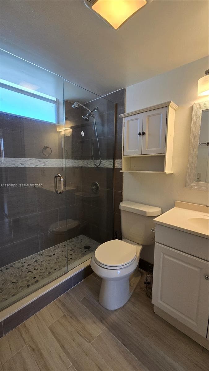 Walk-in shower featuring a glass enclosure, stone-tiled floor, and decorative mosaic accent band