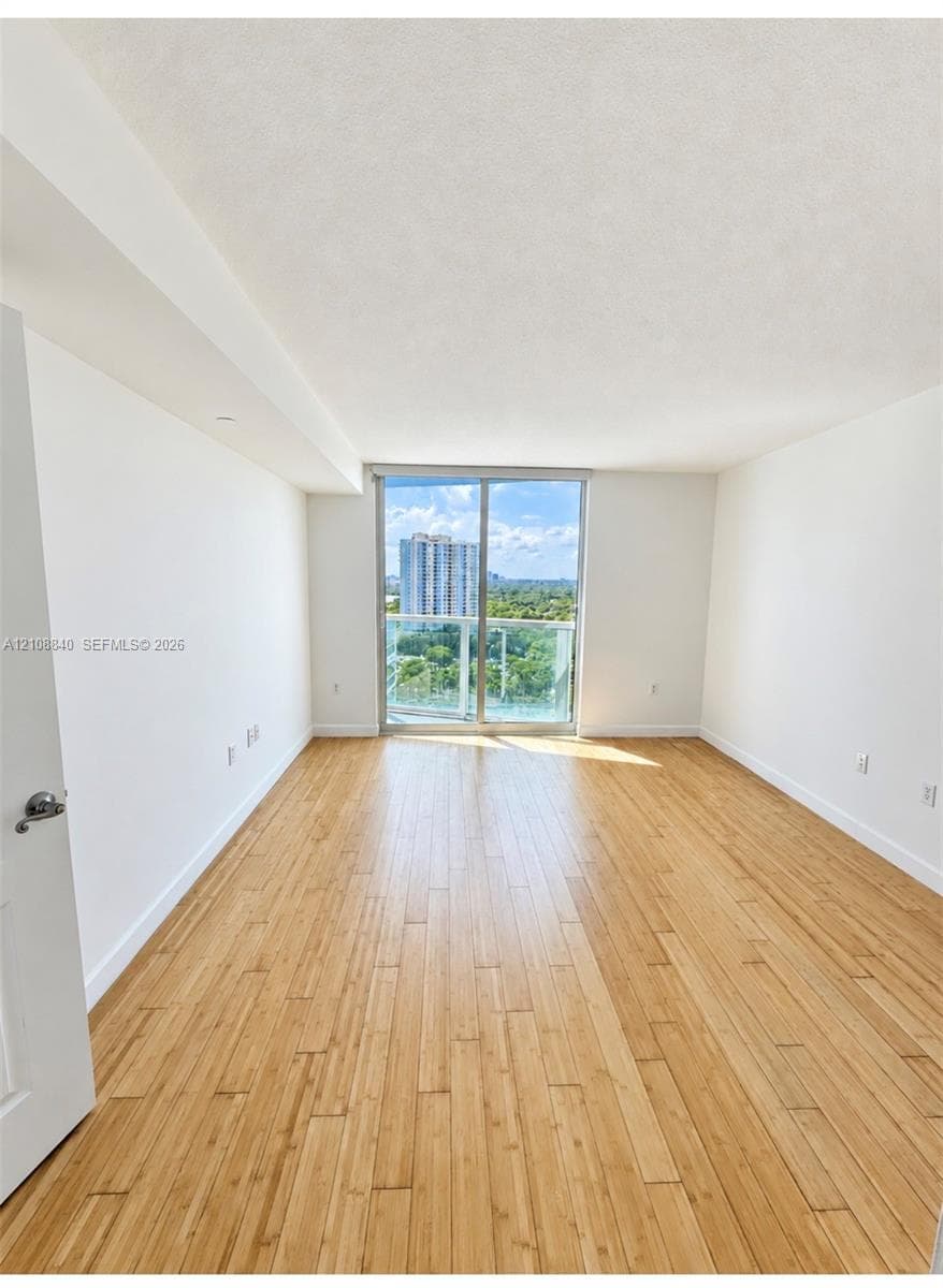 Interior space featuring wood-finish flooring, floor-to-ceiling sliding glass door, and a glass-paneled balcony