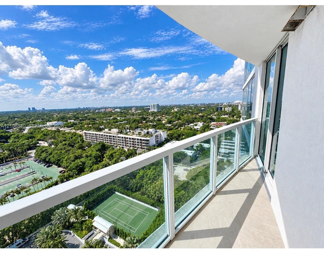 Private balcony with a glass and metal railing, concrete flooring, and full-height sliding glass doors