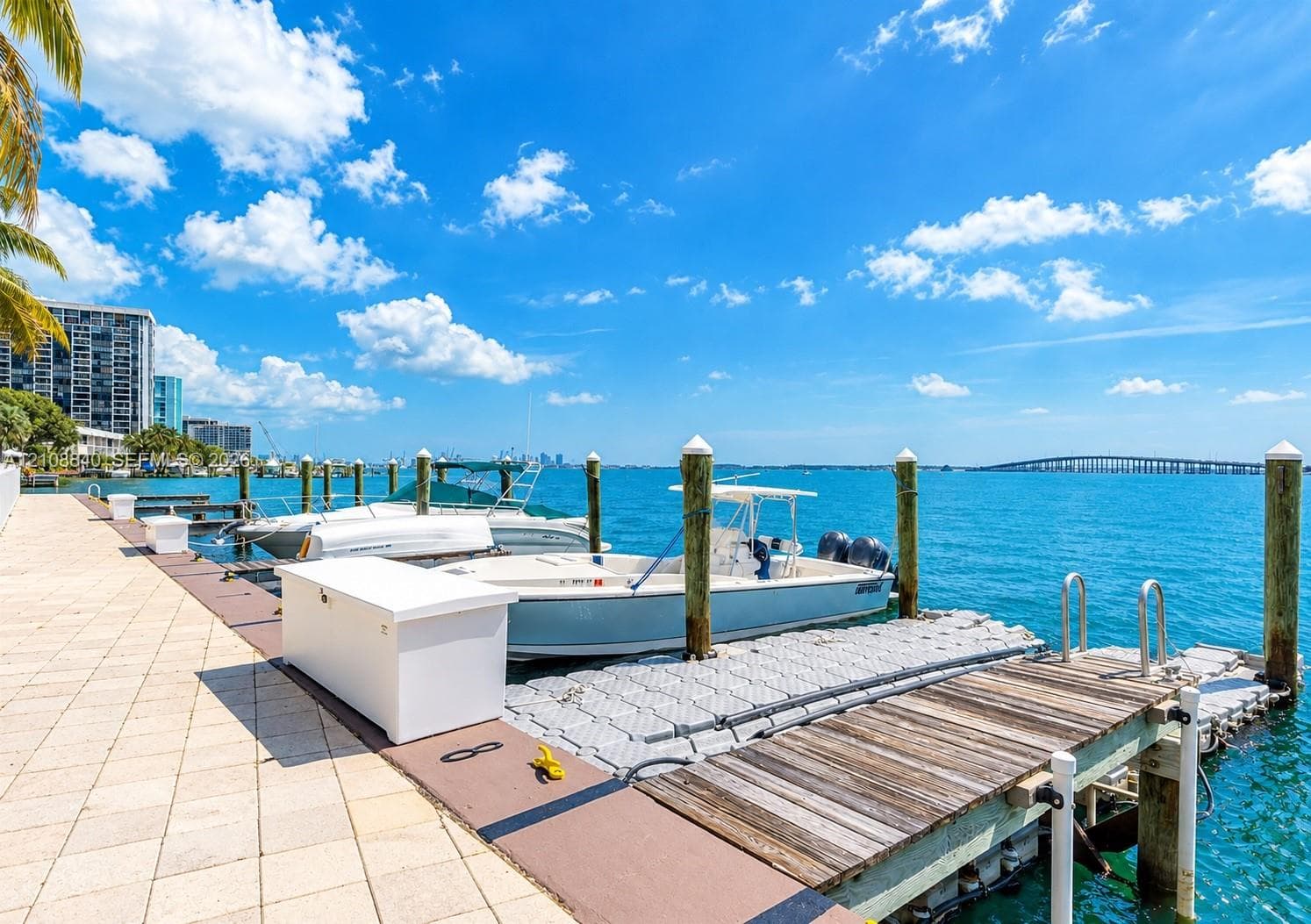 Private deep-water dock featuring multiple pilings, floating modular docking sections, a wooden walkway, and storage locker