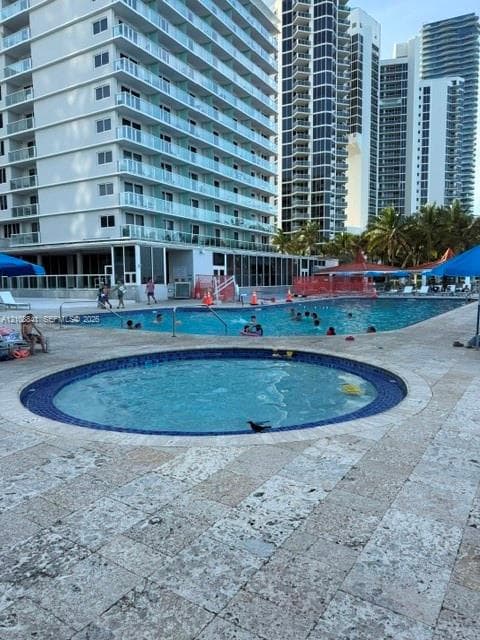 Outdoor swimming pool and circular spa featuring tile finishes and natural stone decking