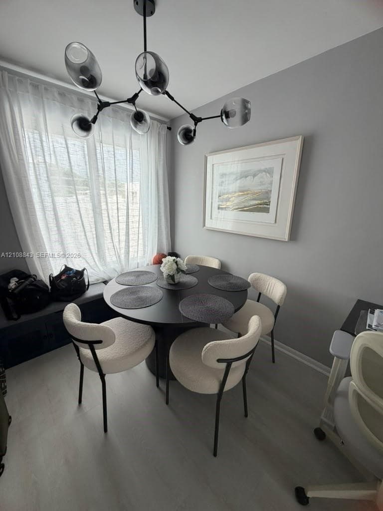 Modern black multi-arm chandelier, built-in window bench with storage cabinetry, and light-toned wood-finish flooring
