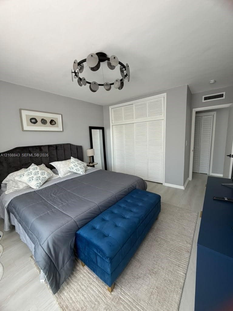 Neutral-toned interior featuring louvered closet doors, light wood-finish flooring, and a decorative circular multi-disk ceiling fixture