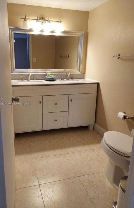Double-sink vanity featuring a neutral countertop, framed wall mirror, polished hardware, and neutral floor tile