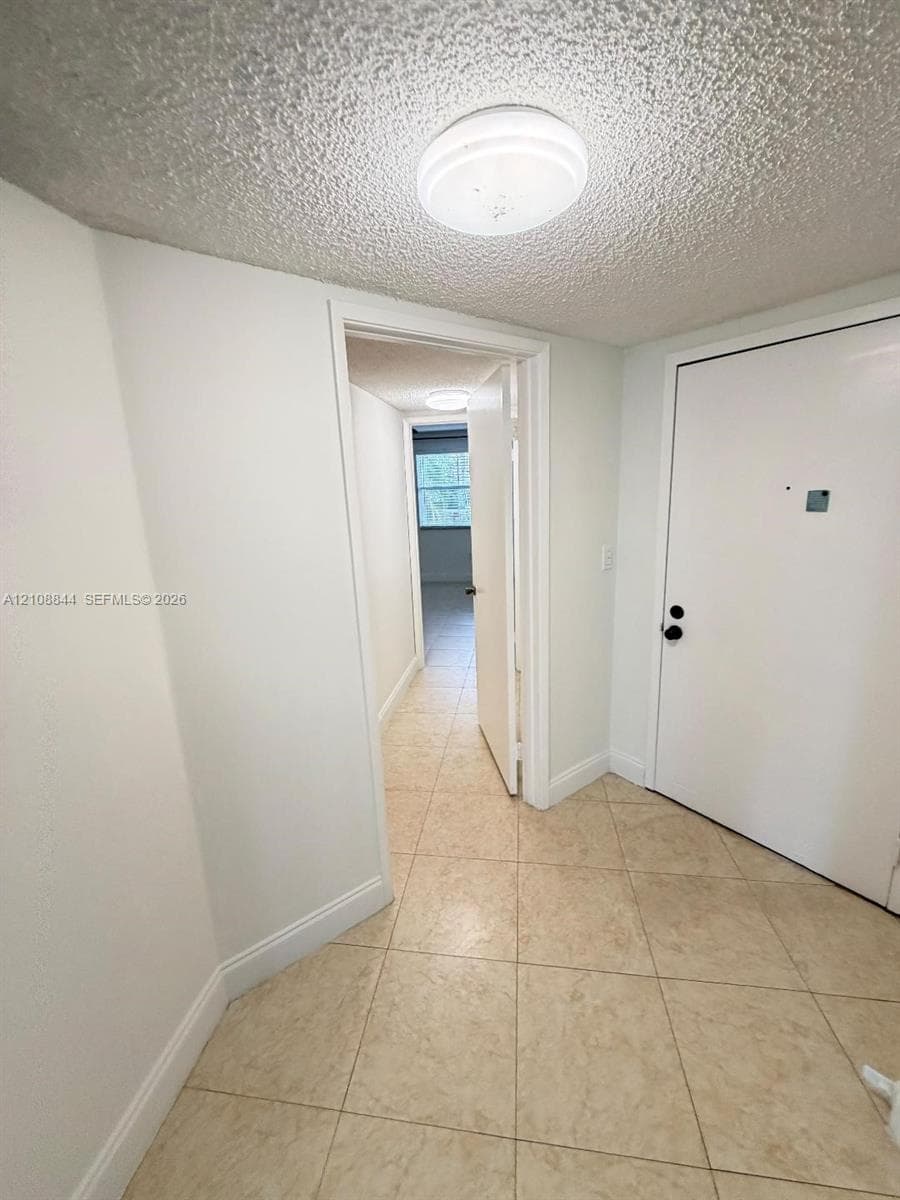 Interior entryway featuring ceramic tile flooring, neutral wall paint, and overhead flush-mount lighting