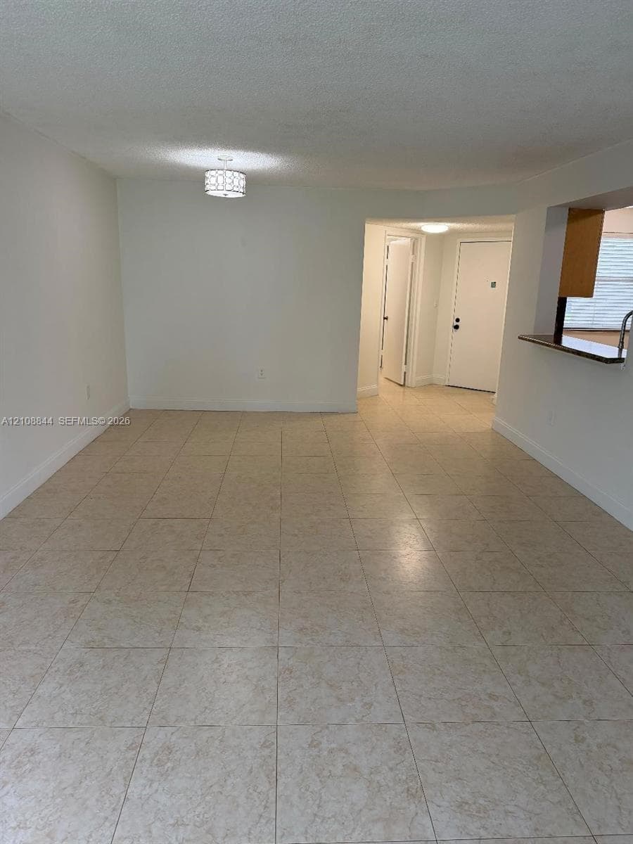 Open-concept floor plan featuring neutral tile flooring, recessed and drum lighting, and a kitchen passthrough with a countertop ledge