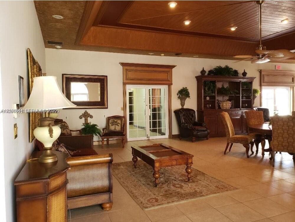 Interior space featuring tray ceiling with recessed lighting, wood-paneled ceiling detailing, built-in cabinetry, tile flooring, and a multi-pane glass entry door