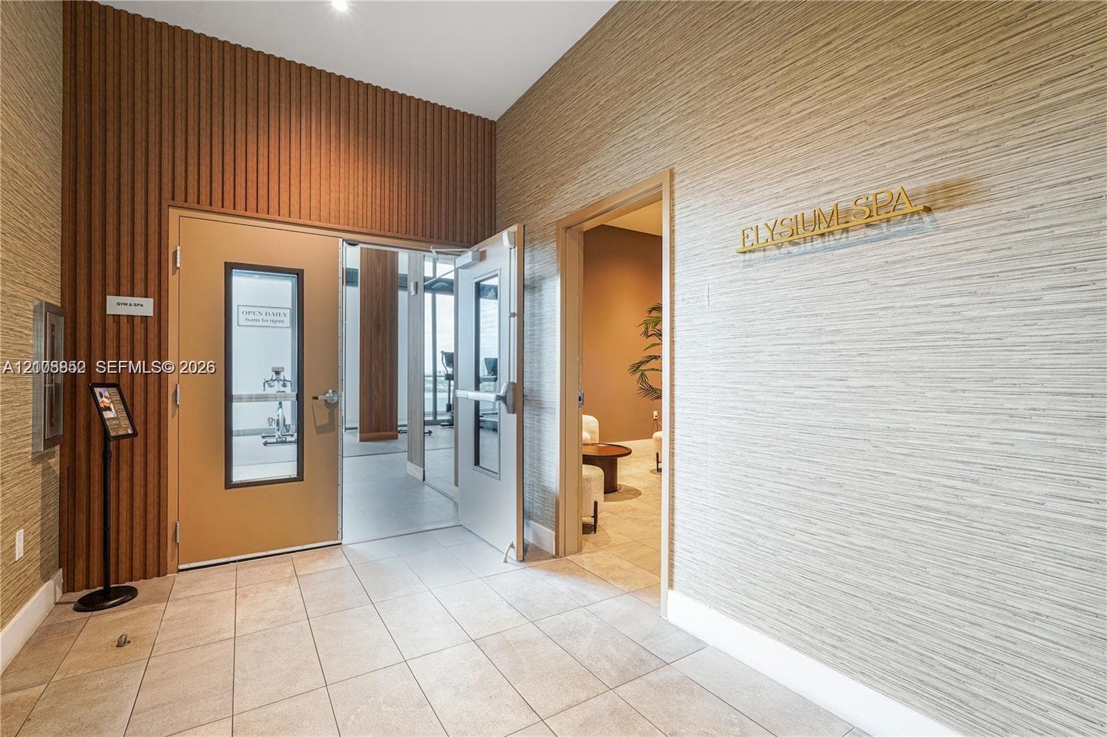 Textured wall coverings, vertical wood-slat accent wall, and ceramic tile flooring throughout the entry area