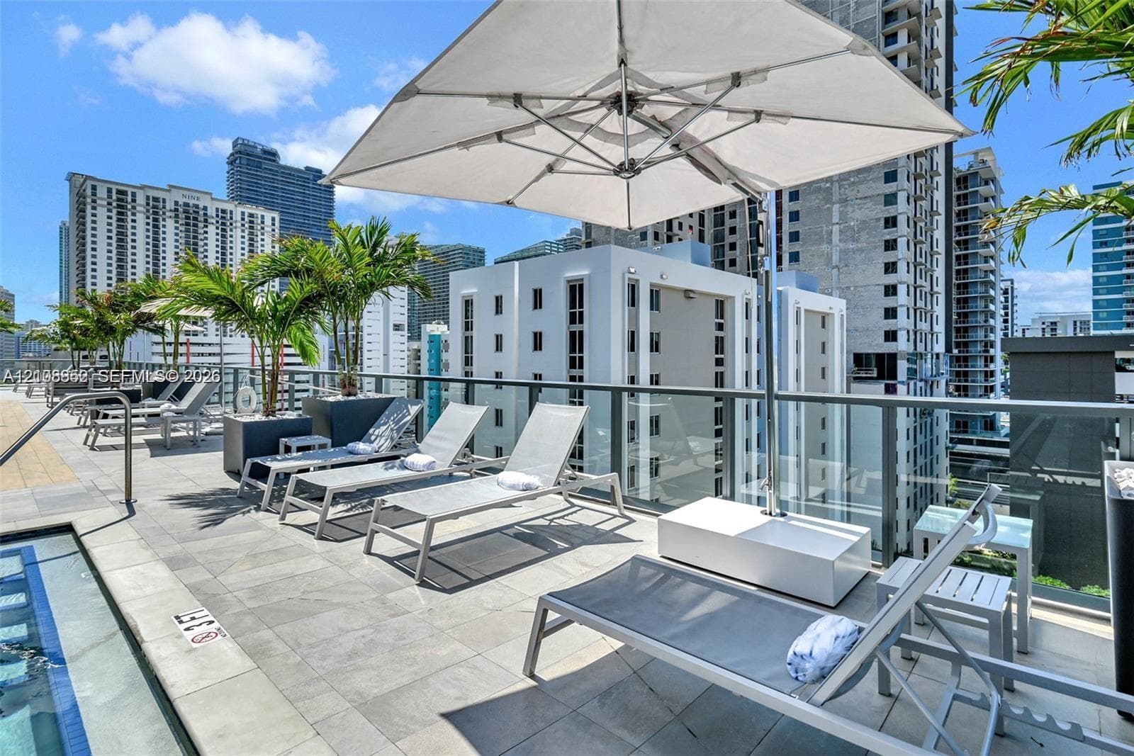 Tiled sundeck terrace featuring a glass-panel perimeter railing, integrated plunge pool, and built-in landscape planters