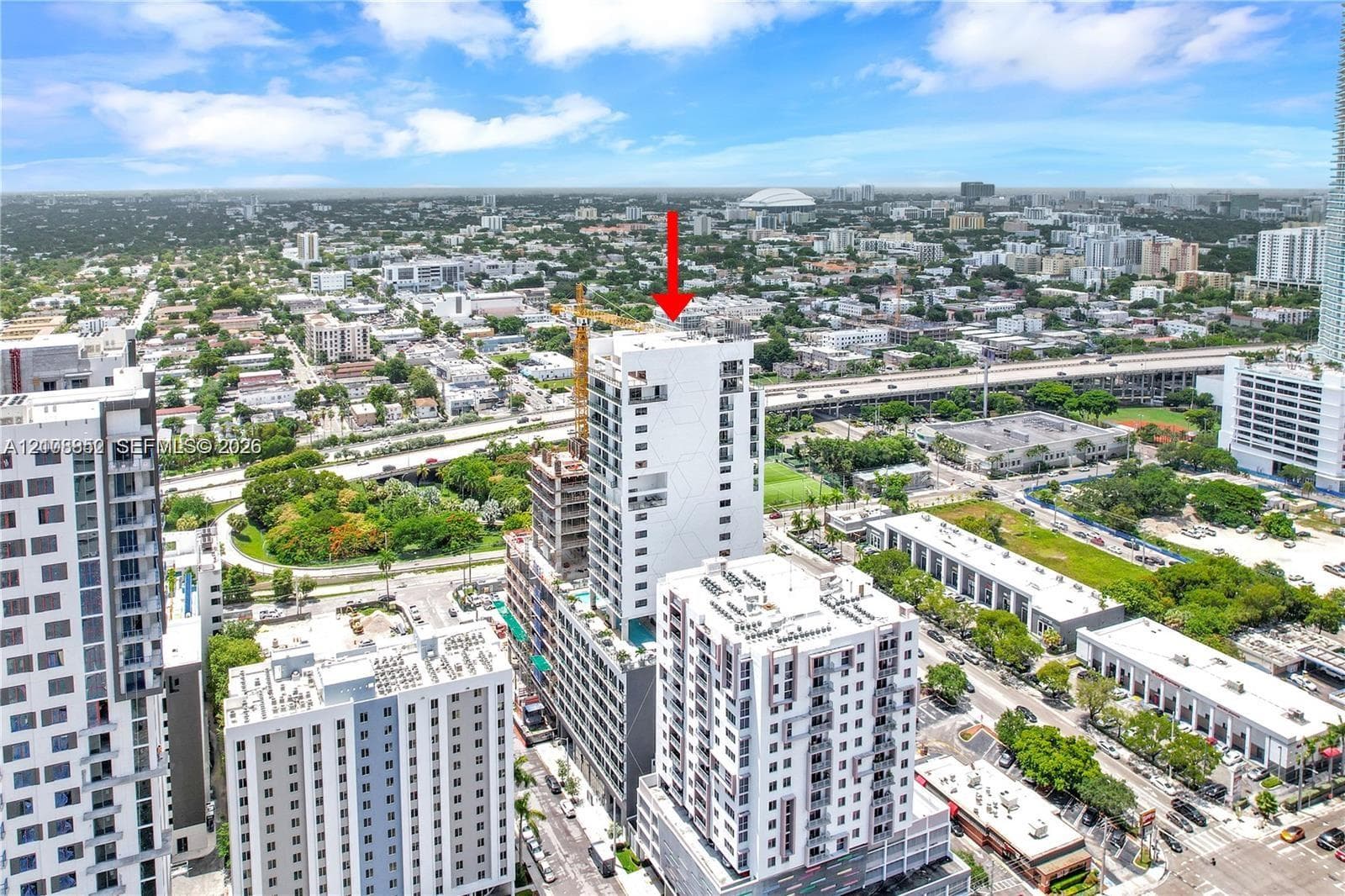 Aerial perspective of a high-rise residential structure featuring a white facade, recessed balconies, and a multi-level architectural design