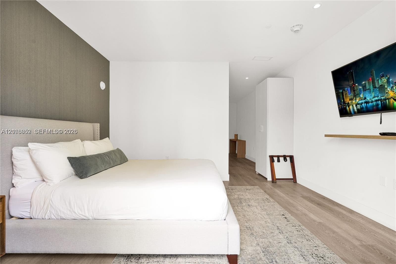 Textured accent wall, wood-finish flooring, and recessed ceiling lighting