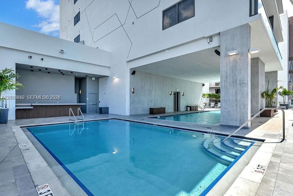 Swimming pool area featuring a built-in bar, recessed lighting, tile decking, and concrete support columns