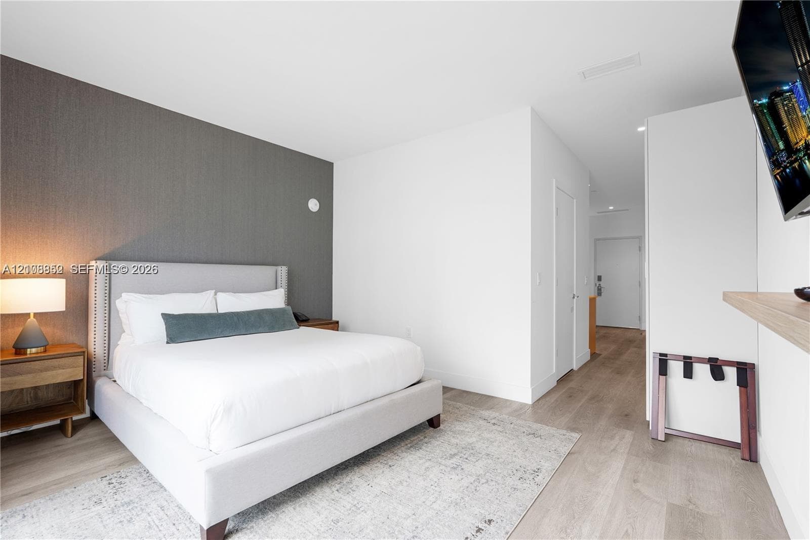 Interior space featuring wood-finish flooring, charcoal-toned accent wall, and a floating wood-shelf fixture