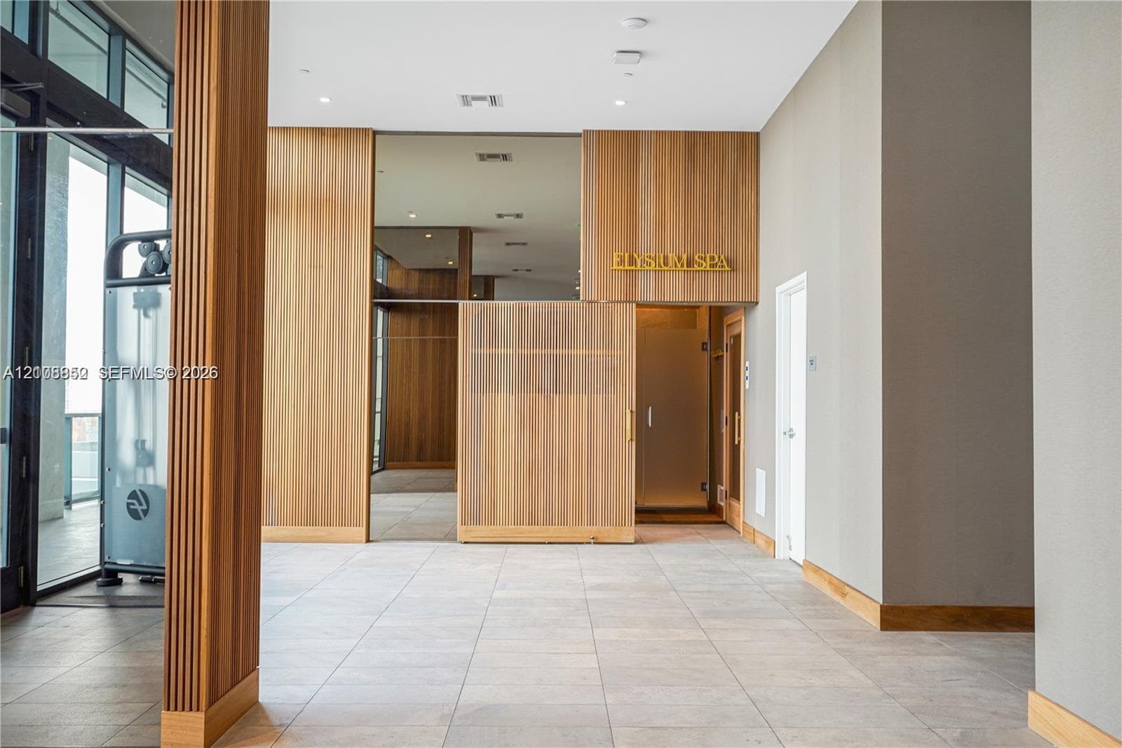 Common area featuring floor-to-ceiling wood-finish paneling, tile flooring, and glass-paneled entryways