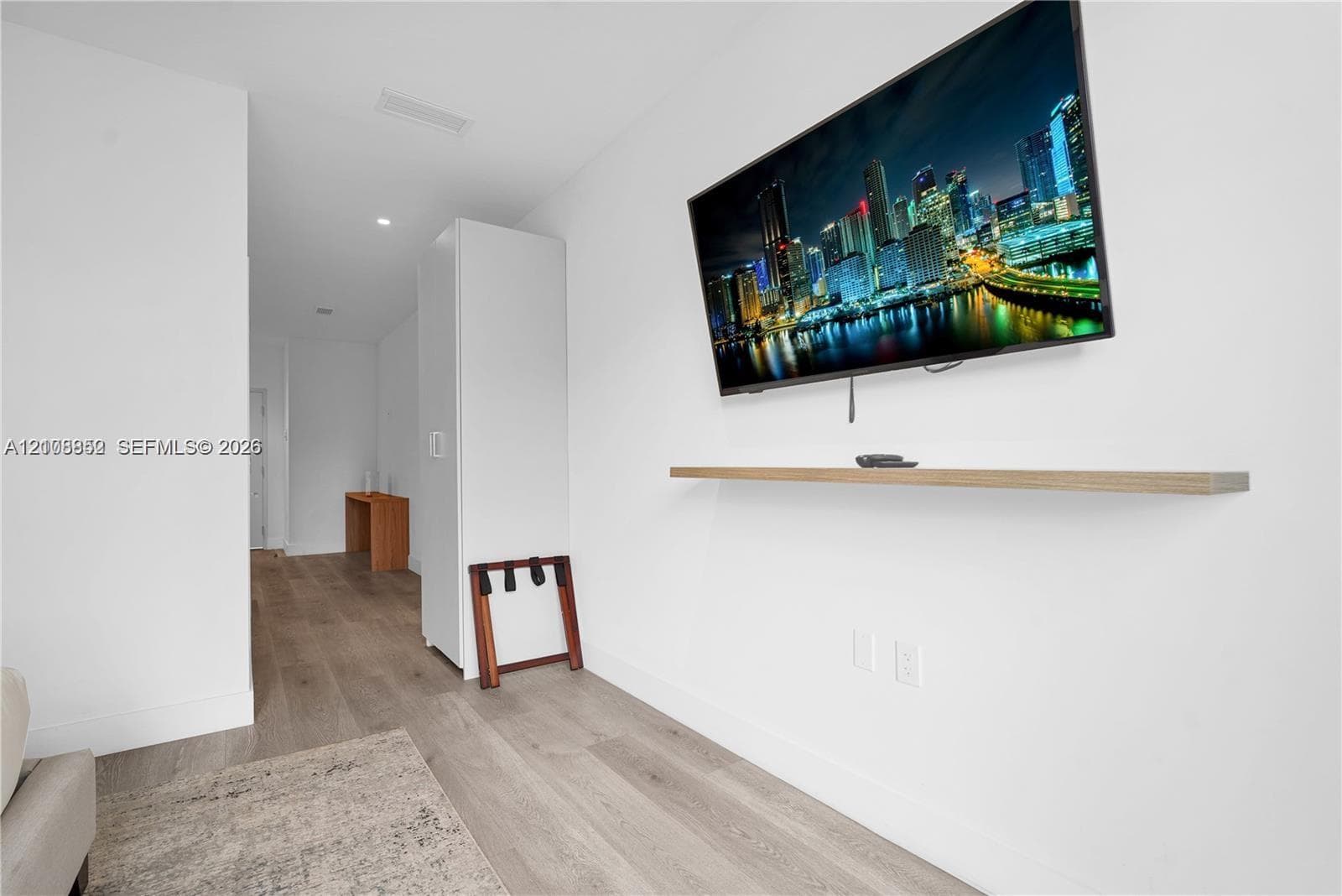 Interior space featuring wood-finish flooring, a neutral color palette, and a built-in wall-mounted floating shelf