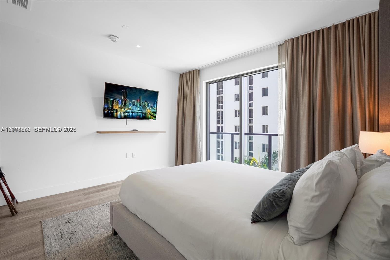 Wood-finish flooring, floor-to-ceiling glass sliding door, integrated wall-mounted shelf, and neutral wall tones