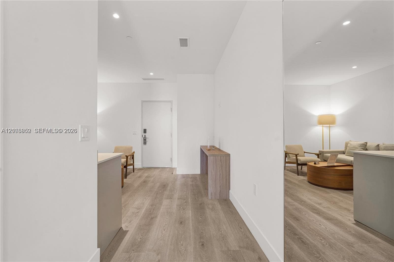 Wood-finish flooring throughout, recessed ceiling lighting, and solid core interior door with integrated hardware