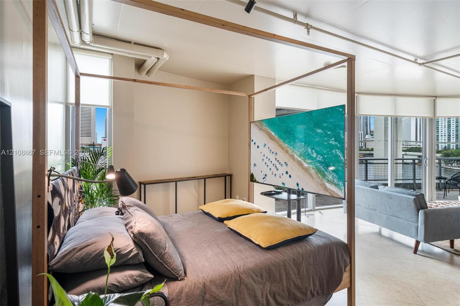 Industrial-style interior featuring exposed overhead piping, concrete flooring, floor-to-ceiling windows, and a private balcony with metal railing