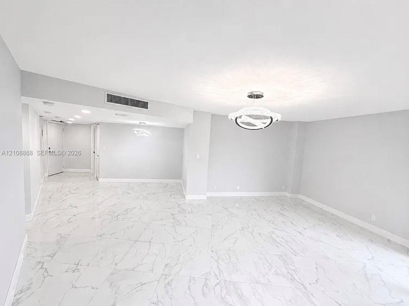 Large-format white tile flooring with grey veining, contemporary integrated circular pendant lighting, and recessed ceiling illumination