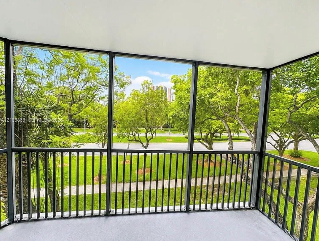 Screened-in balcony featuring a metal railing and concrete flooring
