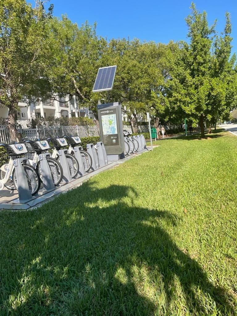 Solar-powered bike share station situated on a manicured lawn featuring mature trees and paved pathways