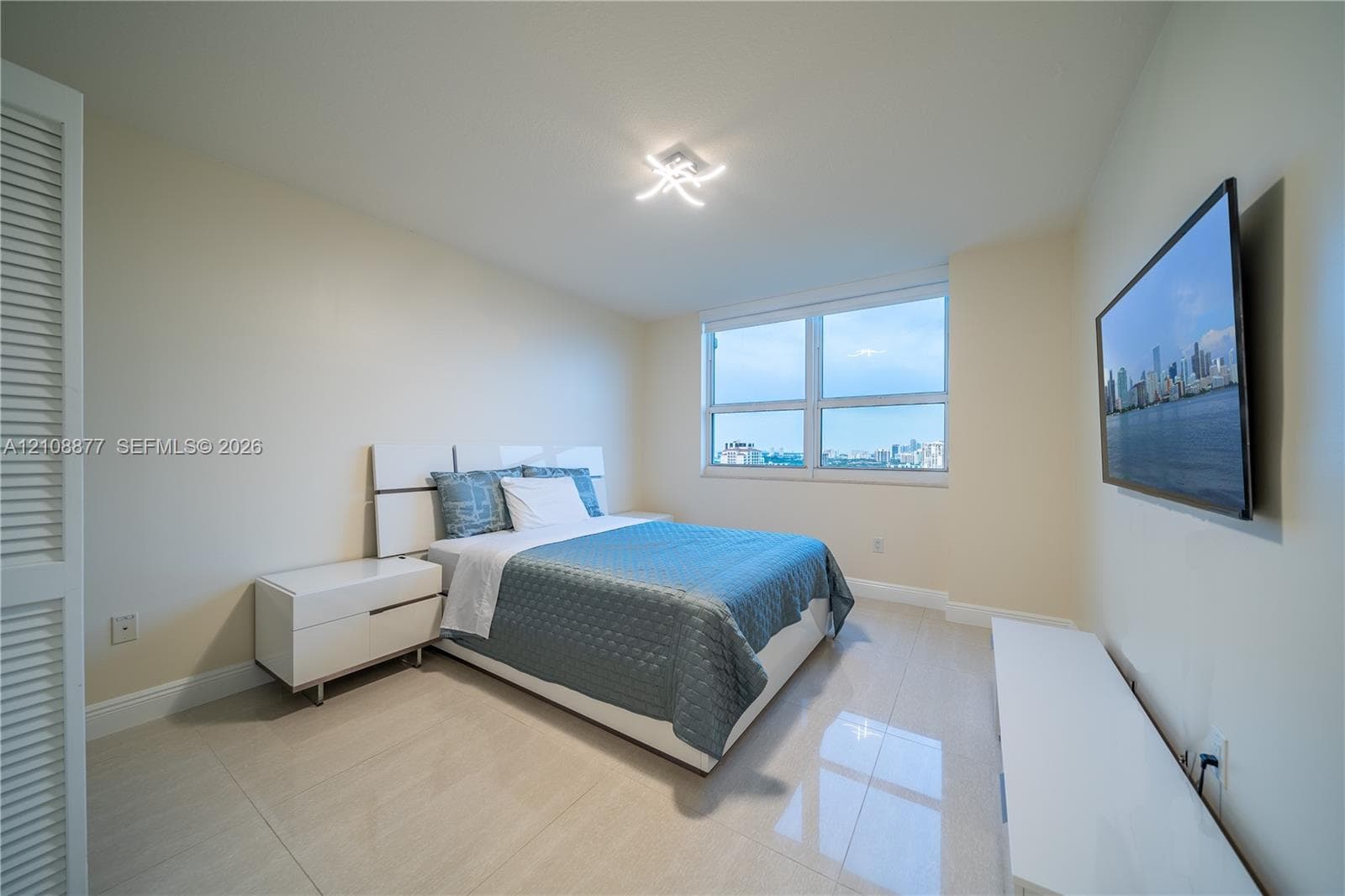 Interior space featuring large-format tile flooring, oversized picture window with urban skyline exposure, and modern contemporary multi-arm flush-mount ceiling light fixture