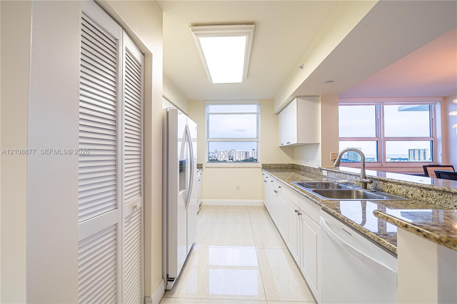 Kitchen featuring stone countertops, white cabinetry, integrated white appliances, louvered closet doors, and tile flooring