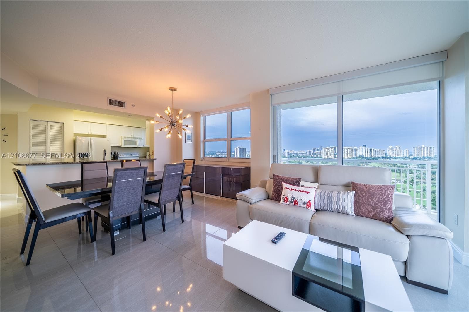 Open-concept living space featuring large-format tile flooring, expansive floor-to-ceiling windows, and a built-in kitchen breakfast bar