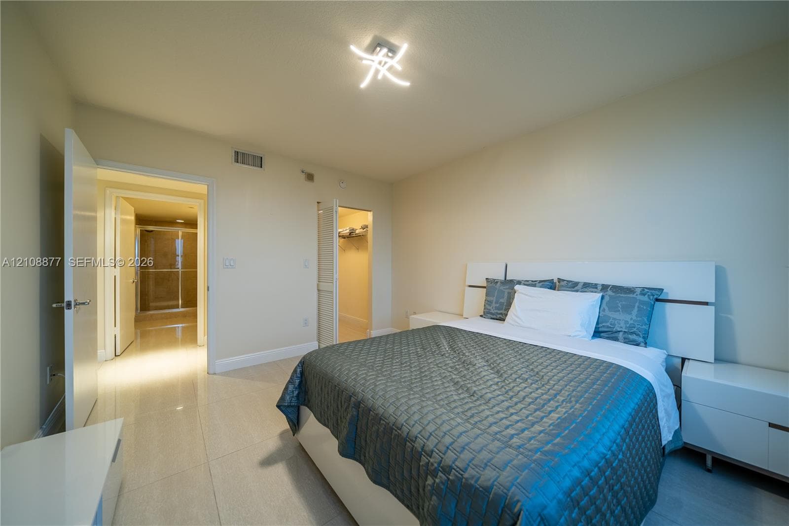 Light-colored tile flooring, modern sculptural ceiling fixture, and neutral wall tones