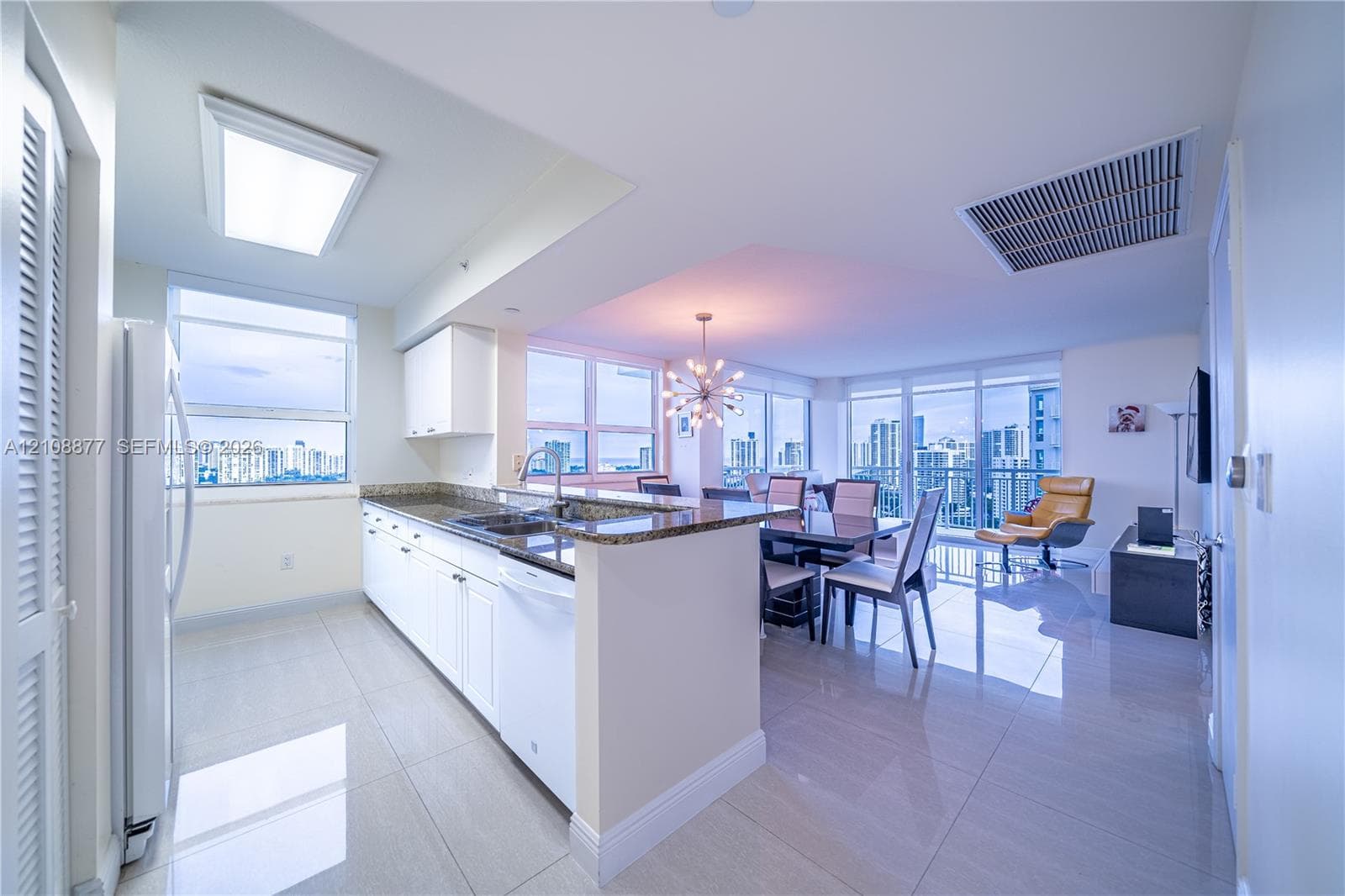 Kitchen featuring white cabinetry, stone countertops, a breakfast bar, polished tile flooring, and floor-to-ceiling windows