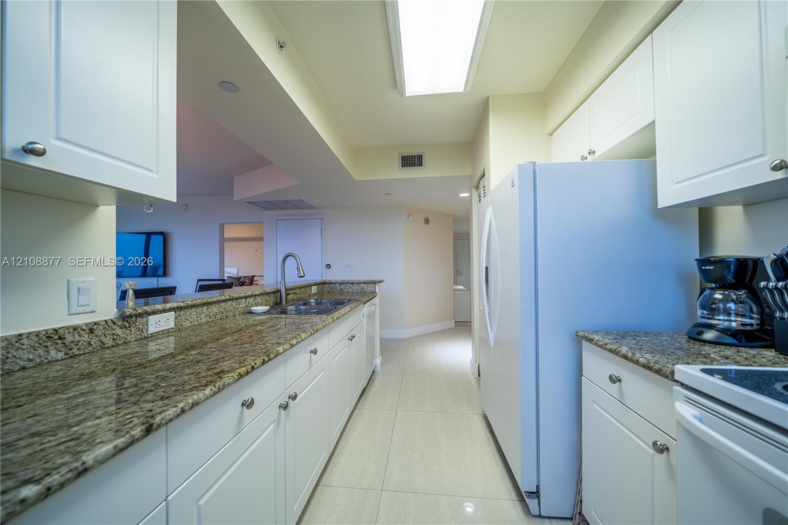 Kitchen featuring white cabinetry, stone countertops, an integrated sink with a gooseneck faucet, tile flooring, and a flat-panel light fixture