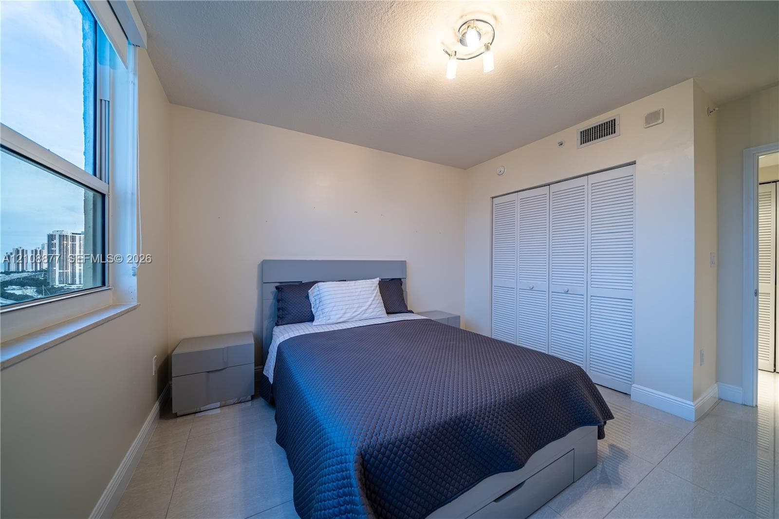 Large window with exterior scenery, tile flooring, and louvered-door built-in closet