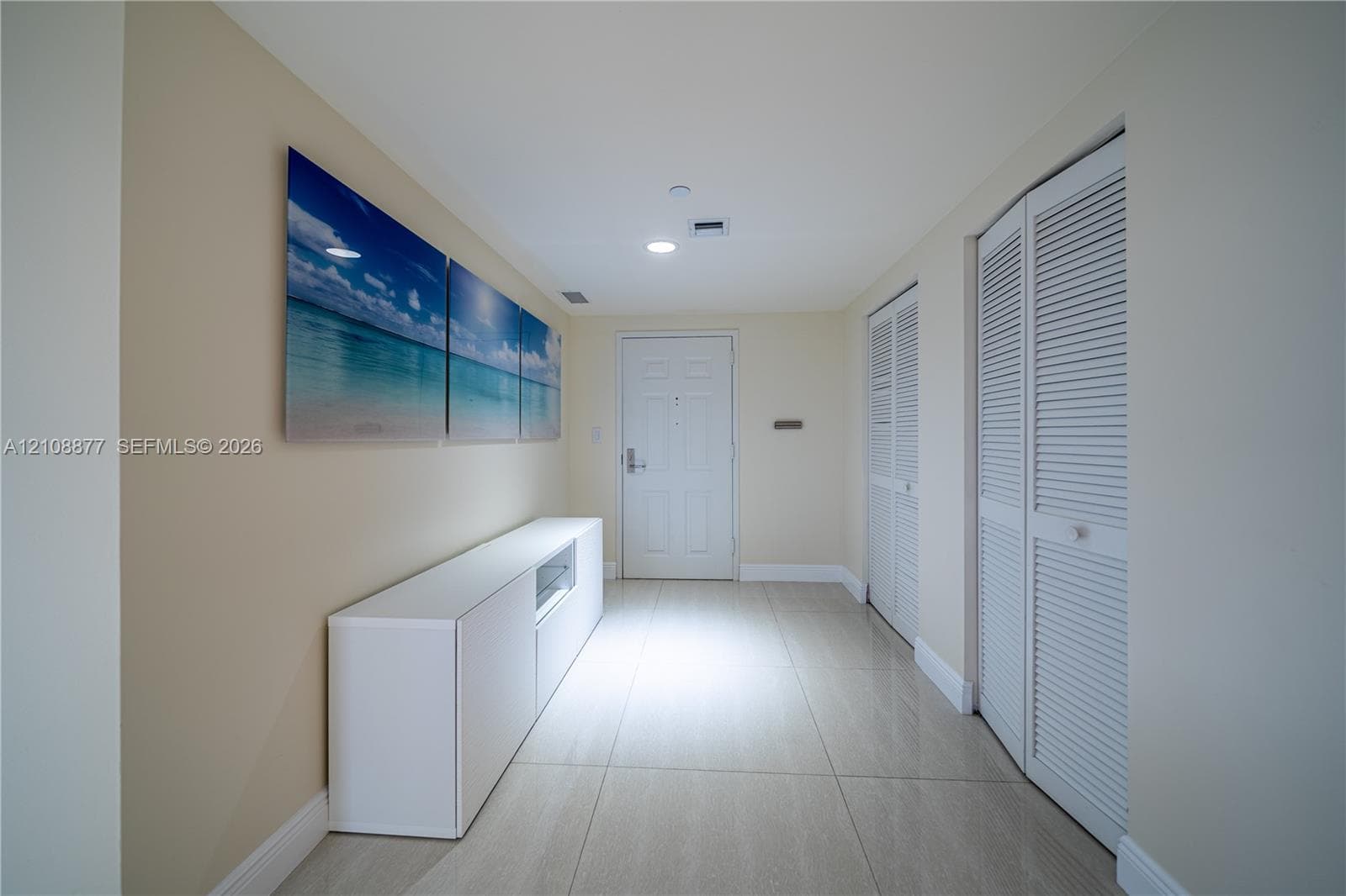 Entryway featuring large-format neutral floor tiling, recessed lighting, and dual louvered closet doors