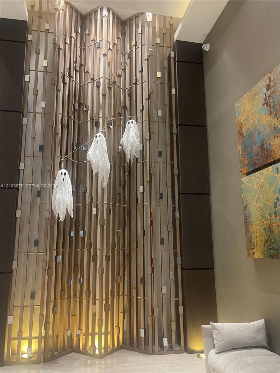 Floor-to-ceiling decorative wood slat wall feature with integrated recessed floor lighting and dark paneled column accents