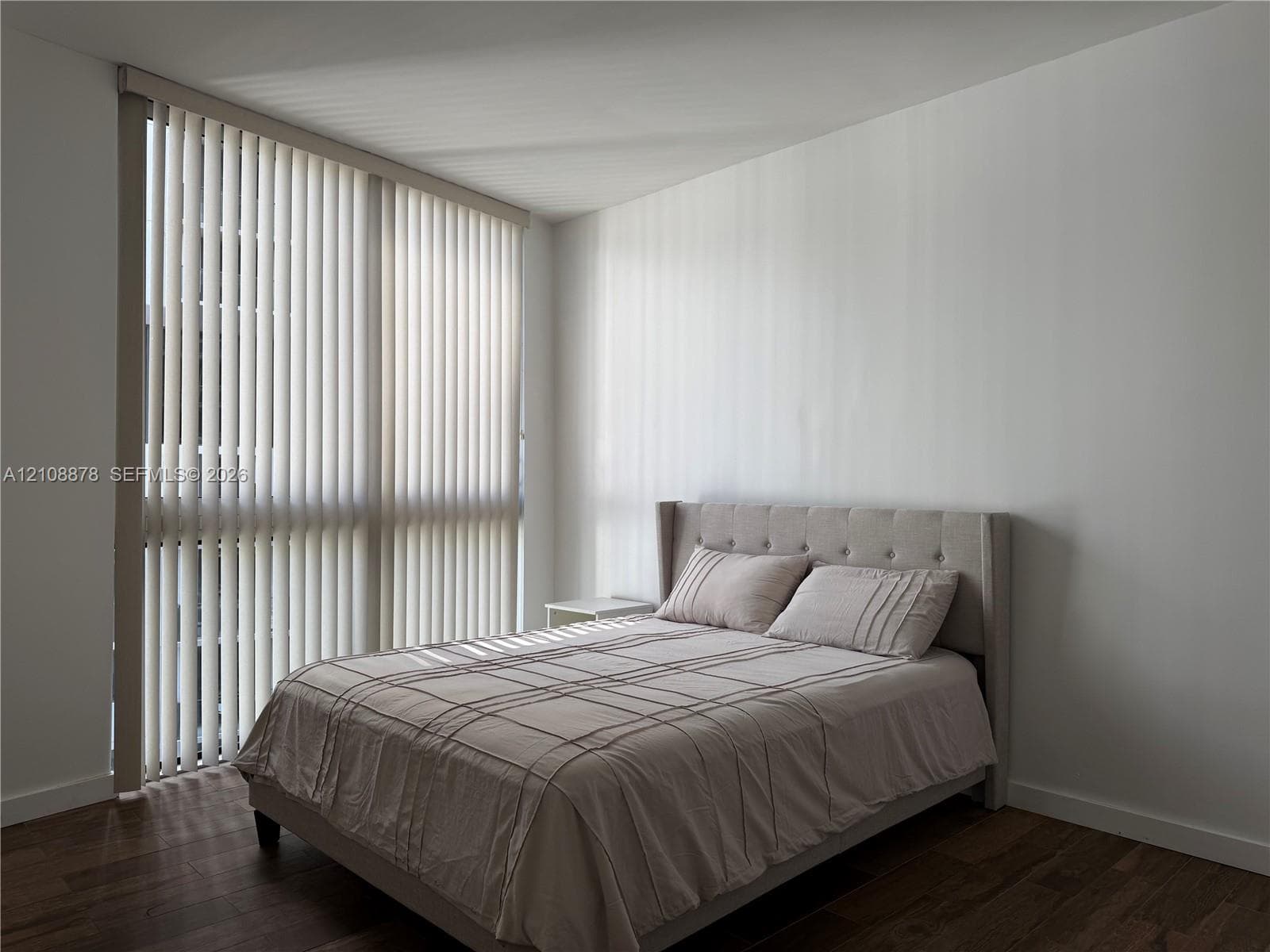 Floor-to-ceiling windows with vertical blinds and wood-finish flooring