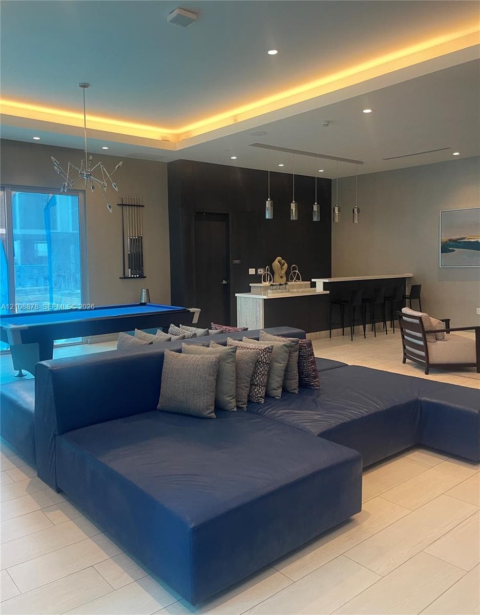 Common area featuring a built-in refreshment bar with stone countertop, recessed ceiling lighting, pendant light fixtures, and tile flooring